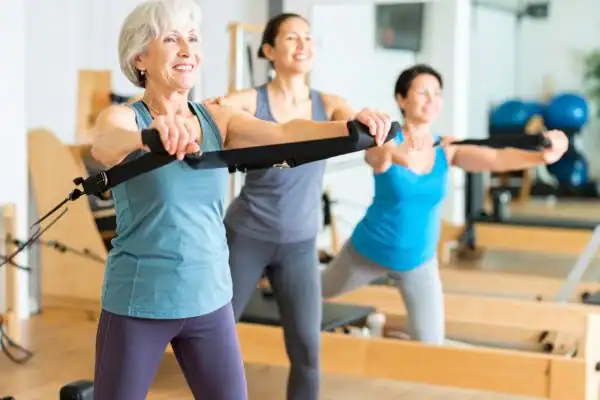 Toning Arms After 60: Empowering Womens Fitness Through Effective Weight Training 2 older woman doing weight training Hampton and resistance in the gym to tone upper arms